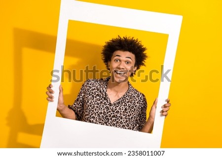 Photo of cheerful excited guy dressed leopard print shirt tacking photo paper photo frame isolated yellow color background