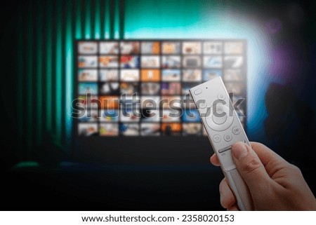 VOD service screen. Man watching TV with remote control in hand. Royalty-Free Stock Photo #2358020153