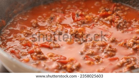 Minced meat and tomato sauce are boiled in a frying pan. Hot steam and bubbles. Cooking bolognese sauce. Food preparation in the kitchen. A series of photos to visualize the recipe.