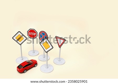 toy red car in front of many road signs on a light background with copy space.