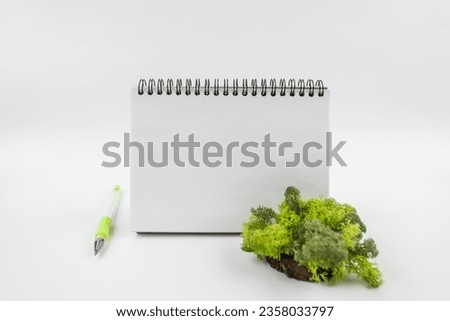 Blank white notepad and plant. New Year. Plans, space for text in a notebook, mock-up calendar on a white background.