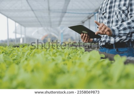 In the Industrial Greenhouse Two Agricultural Engineers Test Plants Health and Analyze Data with Tablet Computer.