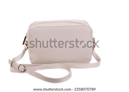 Tiny beige leather cross-body bag isolated against a white background with space for text. Concept of versatile female accessories. Fashion blog. Advertising for boutiques and shops. Royalty-Free Stock Photo #2358070789
