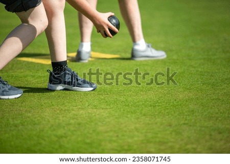 close up photo of legs of people playing bowls on a summer sunny day