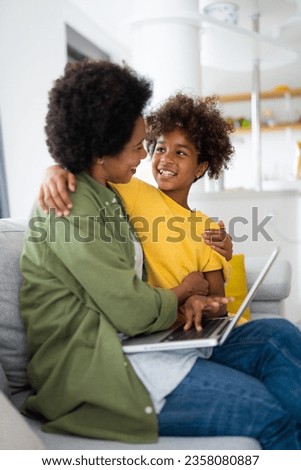 Close up of happy African American mother and daughter embracing each other while watching movie on laptop.