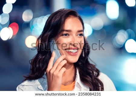 Lifestyle portrait of beautiful happy woman talking on cellphone, looking aside and smiling, walking at city street full of neon lights at night, closeup, copy space Royalty-Free Stock Photo #2358084231