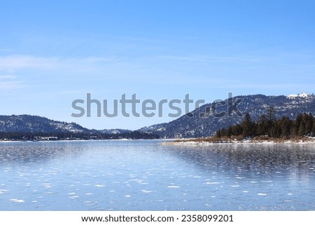 Big Bear Lake with ice floating on the water and the snowed mountains on the background during the winter.