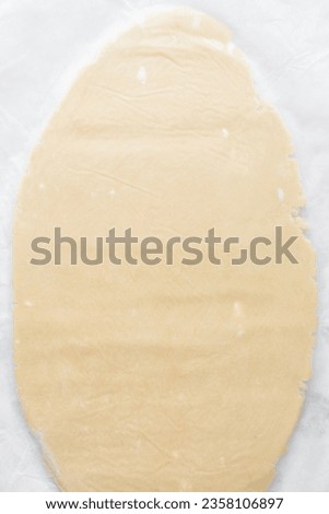 Top view of sugar cookie dough rolled between parchment paper, process of making cut out sugar cookies Royalty-Free Stock Photo #2358106897