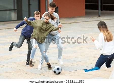 Two teenage boys and two cute girls play ball near the school building Royalty-Free Stock Photo #2358111551