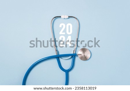 Stethoscope and white numbers 2024 on blue background. Concept of health care in the New Year. Medical calendar. Copy space
