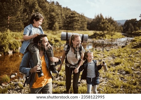 Young family crossing a creek while hiking in the forest and mountains Royalty-Free Stock Photo #2358122995