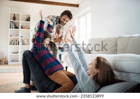 Young family playing with each other and having fun in the living room at home Royalty-Free Stock Photo #2358123899