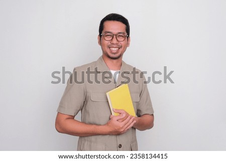 Indonesia young teacher smiling happy while holding a book Royalty-Free Stock Photo #2358134415