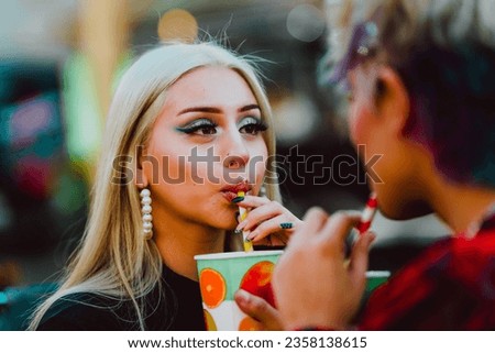 Woman drinking soda with a straw while enjoying with her friend. Friendship concept.