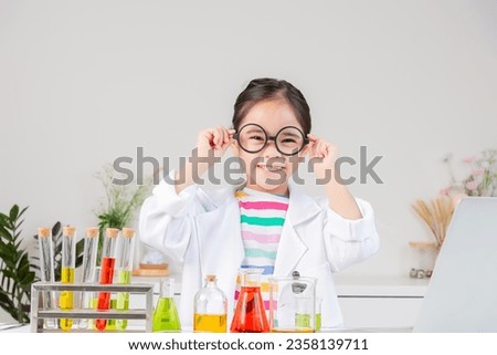 little girl Wear a science ground shirt working with test tube science experiment in white room