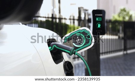 Electric car recharge with EV charger at futuristic car park utilization of charging station display battery status hologram for rechargeable EV car using alternative and sustainable energy.Peruse