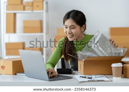 Asian businesswoman packing products in boxes preparing for order delivery and use a laptop computer to check customer orders online. ecommerce business ideas