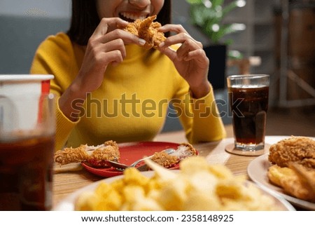Happy Asian young woman eating delicious crispy fried chicken in the living room at home. family party Smile, laugh, enjoy food and drink, lifestyle concept, celebrate holidays.