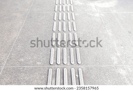Stainless steel Tactile paving with textured ground surface on the side street. Metal ornament on walk path dedicated to group of disability blind people