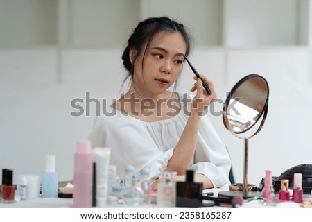 Asian female video blogger to review cosmetics. Influencer beauty blogger broadcasts makeup tools, lipsticks, powders, buffs, perfumes how to do makeup for social followers in the office 