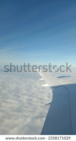 portrait picture of the plane wing in the air. Taken in the morning above the cloud.