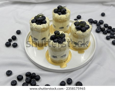 Blueberry shortcake on a wooden plate. Very shallow depth of field. Fresh Blueberry  topping with cream and yellow flower. Bakery picture free space for text.
