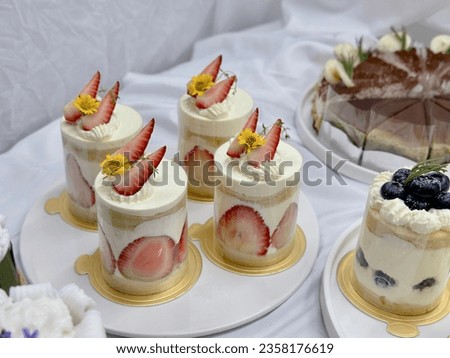 Strawberry shortcake on a wooden plate. strawberry blueberry  topping Very shallow depth of field. Fresh Strawberry  topping with cream and yellow flower. Bakery picture free space for text