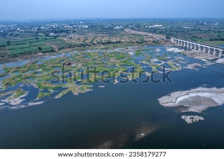 Aerial footage of the River Bhima and surrounding landscape including bridges at Daund India. Royalty-Free Stock Photo #2358179277