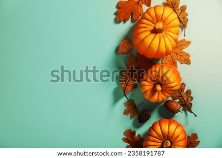 Autumn background creative layout with decorative small pumpkins and autumn leaves. Flat-lay on a blue background, top view copy space