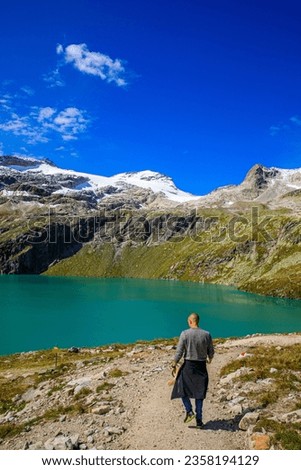 Man walking near a deep blue lake at the Weissee, Weißsee Gletscherwelt, ski area in Salzburgerland, Austria Royalty-Free Stock Photo #2358194129