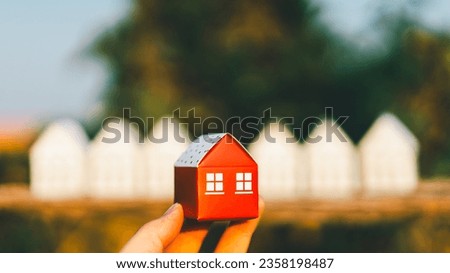 Hand choosing mini house model from model on wood table, selective focus, Planning to buy property. Choose what's the best. A symbol for construction ,ecology, loan concepts