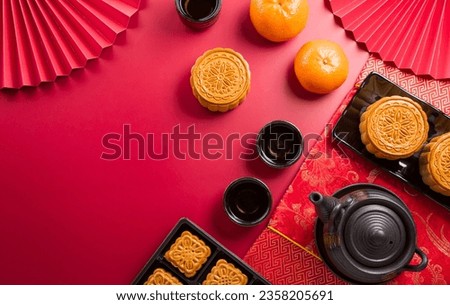 Chinese Mid-Autumn Festival concept made from mooncakes, tea and plum blossom on red background.