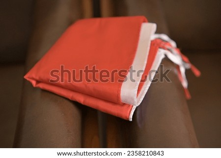 red and white cloth folded on a brown chair