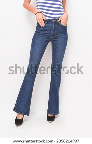 Half female in striped t-shirt  with blue jeans with black, high hell shoes posing  in studio