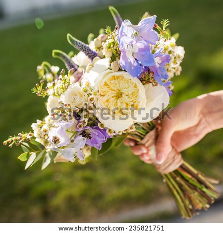 Bouquet of flowers in hand on a grass background.