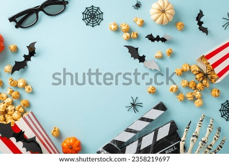Halloween Movie Magic: Top view of thematic cinema embellishments. Popcorn boxes, creepy spiders, undead skeleton hand, and assorted eerie elements on pastel blue, featuring frame for text or advert