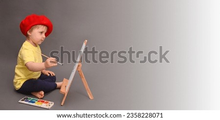a little girl paints a picture with watercolor paints. on a gray background.