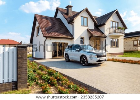 A white house with a flower bed and flowers, as well as a white car in front of the house. Royalty-Free Stock Photo #2358235207