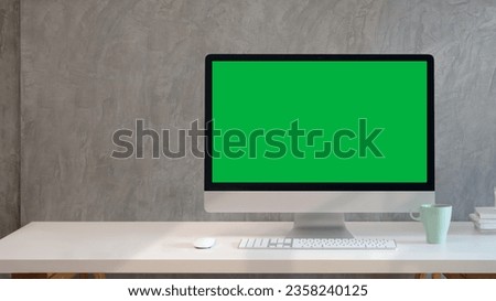 Desktop computer with Green Screen and keyboard on the table.The Background Bright Creative Loft for Developers and Designers where Professional Working.