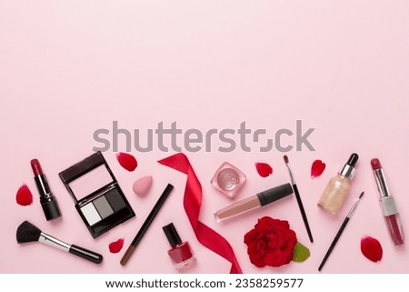 Flat lay with makeup products and tools with flowers on color background