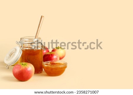 Jar and glass bowl of sweet apple jam on orange background