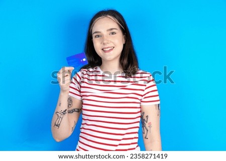 Photo of happy cheerful smiling positive Young caucasian woman wearing striped t-shirt recommend credit card