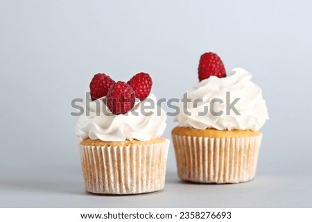 Tasty raspberry cupcakes on grey background Royalty-Free Stock Photo #2358276693