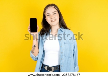 Smiling young caucasian woman wearing casual clothes Mock up copy space. Hold mobile phone with blank empty screen