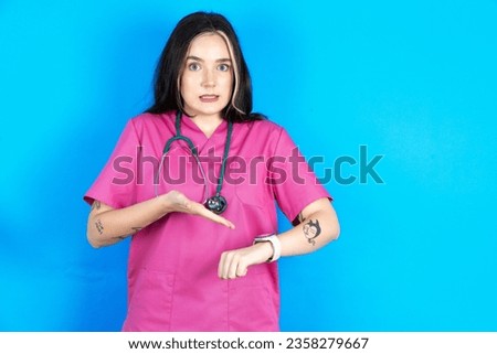 Young caucasian doctor woman wearing pink uniform In hurry pointing to watch time, impatience, upset and angry for deadline delay. Royalty-Free Stock Photo #2358279667