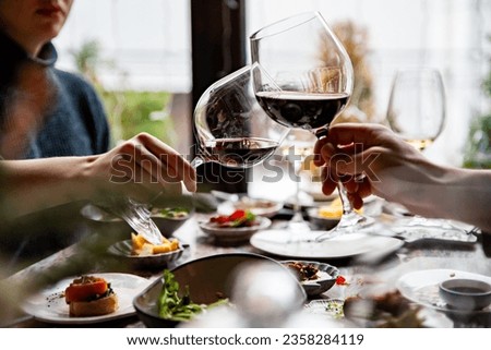 Close up of hands young couple man and woman clinking with glasses of red wine at restaurant Royalty-Free Stock Photo #2358284119