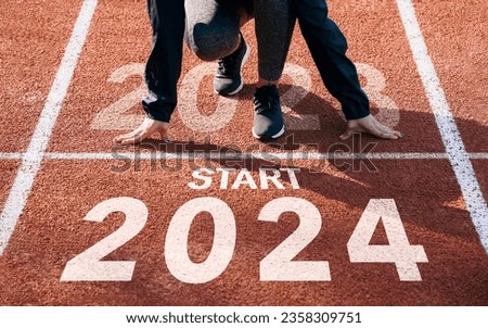 happy new year 2024 symbolizes the start of the new year. Rear view of a man preparing to run on the athletics track engraved with the year 2024. The goal of Success.Getting ready for the new year Royalty-Free Stock Photo #2358309751