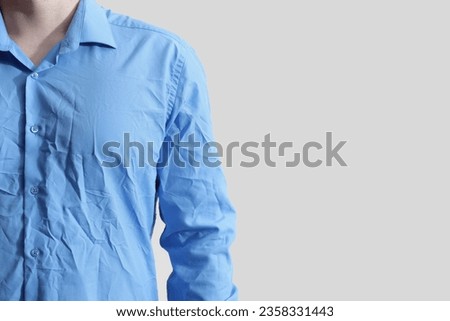 Man wearing creased shirt on light background, closeup. Space for text Royalty-Free Stock Photo #2358331443