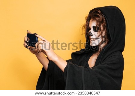 A studio shot of a girl taking a selfie in a costume of evil spirits at a Halloween costume party. Empty space for goods, advertising. The Art of Halloween