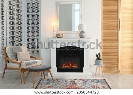 Beautiful fireplace, armchair and ottoman in living room. Interior design Royalty-Free Stock Photo #2358344723